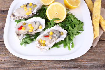 Tasty cooked oysters in shell on wooden table