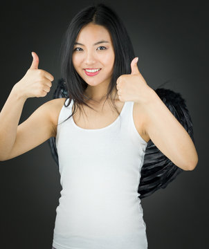 Asian young woman dressed up as an angel showing thumb up sign