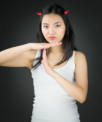Asian young woman in devil horns making time out signal with