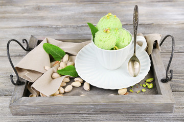 Tasty pistachio ice cream in cup on wooden table