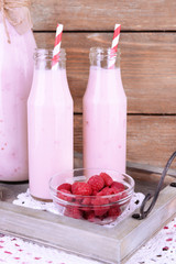 Bottles of raspberry smoothie drink on wooden background