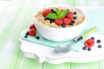 Tasty oatmeal with berries on table close-up