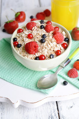 Tasty oatmeal with berries on table close-up