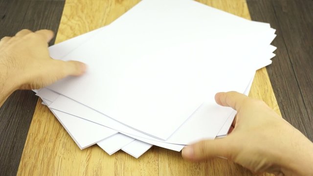 Man organise empty white paper size A4 on wood background