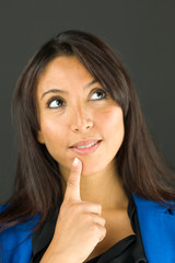 Naklejka premium Thoughtful young businesswoman looking up with her finger on