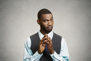 Headshot sly, scheming businessman on grey wall background