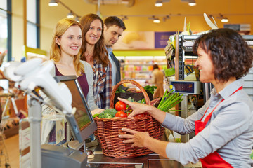 Frau bezahlt Gemüse an der Kasse im Supermarkt