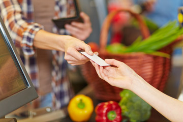 Hand zeigt Kundenkarte an Kasse im Supermarkt