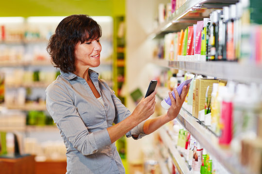 Frau mit Smartphone scannt Produkt im Supermarkt
