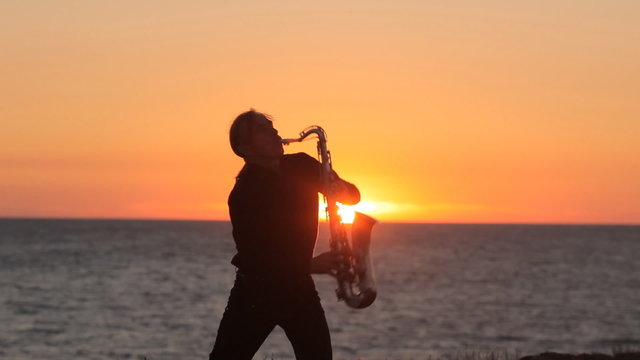 The silhouette of a musician playing saxophone on the seacoast