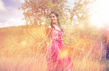 Young woman in dirndl walking alone in the field