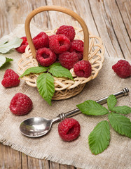 Small basket with fresh raspberries on wooden background