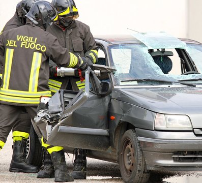 brave firefighters with pneumatic shears cut the sheets of car
