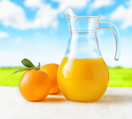 Jug of orange juice on nature background