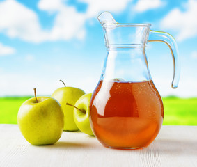 Jug of apple juice on nature background