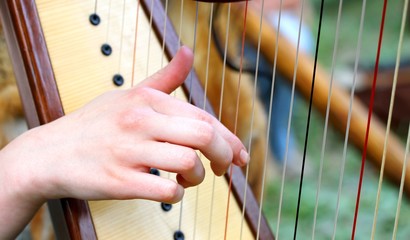 hand while plucking the strings of a harp