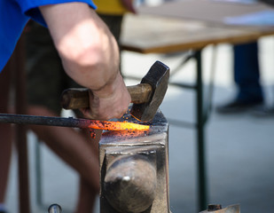 Blacksmith forges a red-hot iron in the forge