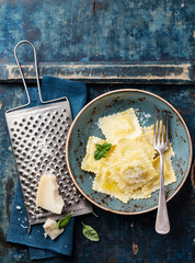 Ravioli pasta with mozzarella cheese, basil and parmesan on blue