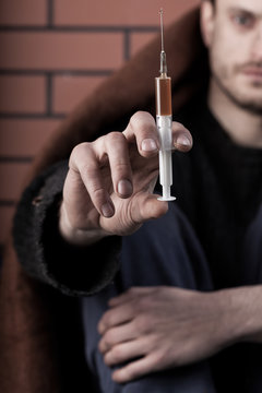 Homeless drug addict man with syringe in hand