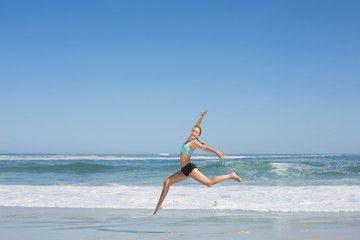 Fototapeta na wymiar Fit woman jumping gracefully on the beach