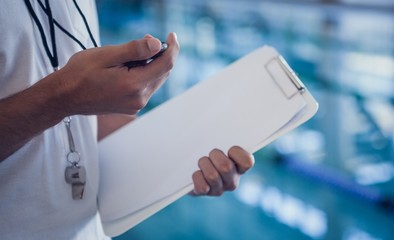 Swimming coach looking at his stopwatch by the pool