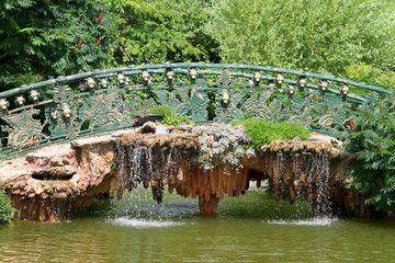 Decorative bridge over green lake surrounded by shrubs