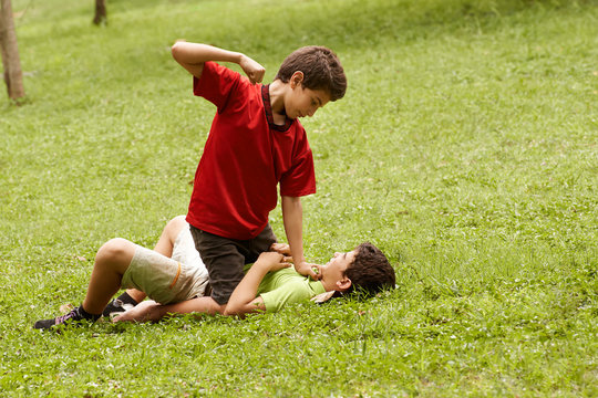 Violent kid fighting and hitting scared boy in park