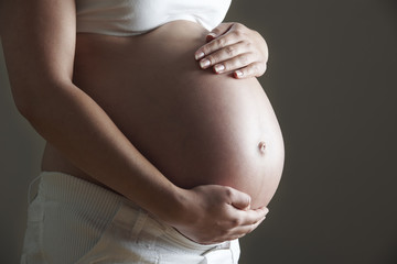 Low Key Image Of Pregnant Woman Holding Belly