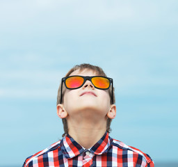 Portrait of a happy boy in sunglasses looking up