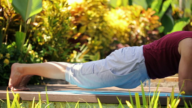 Young Man Doing Plank Exercise On Wooden Platform In The Garden