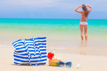 back view of a woman in bikini and straw hat with beach bag and