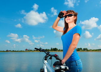 Fototapeta na wymiar Young woman is standing behind of her bicycle