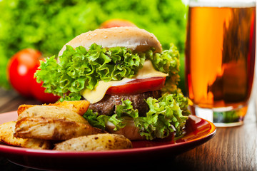 Cheeseburger with fried potatoes on a plate with beer