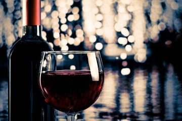 red wine glass near bottle with light bokeh