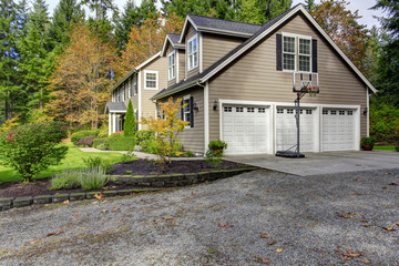 House exterior. View of three car garage with driveway and baske