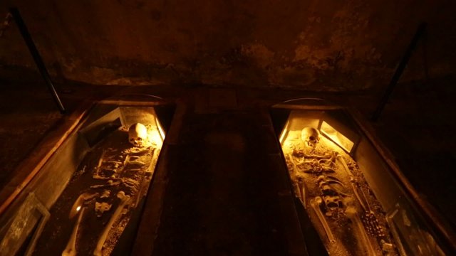 Skeletons laid down in a cave.  Dark but with yellow tones