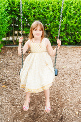 Summer portrait of a cute little girl playing on playground
