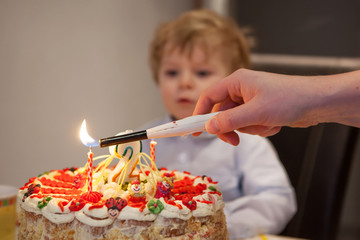 Little toddler blowing candles on his 2 birthday cake