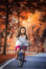 Obraz premium Little girl riding a bicycle in the park