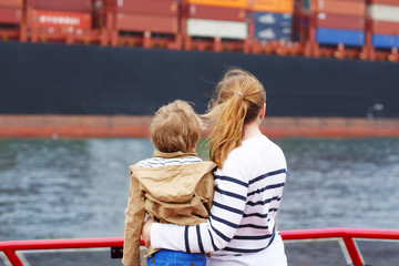 Little boy and mother watching ships on a ferry.