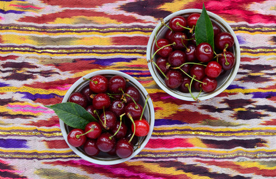 Bowls with ripe cherry over bright oriental tablecloth