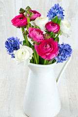 ranunculus and hyacinth flowers in a pitcher