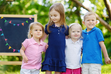 Four excited little kids by a chalkboard