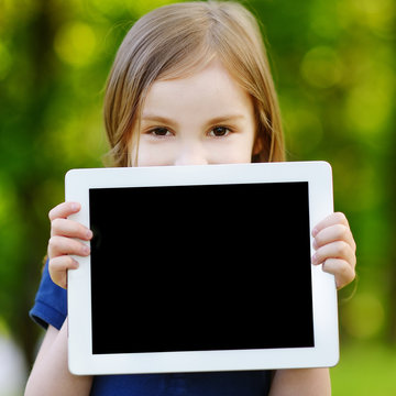 Happy child holding tablet PC outdoors