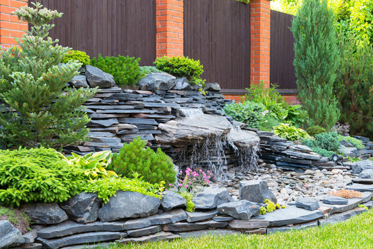 Landscape design in home garden, stones and waterfall in backyard