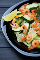 Salad with shrimps, cucumbers and lime in a glass plate