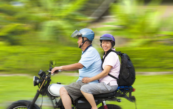 senior couple driving motorcycle with dynamic background