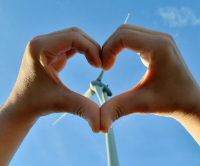 Heart from hands with a wind turbine in the background