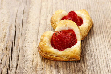 Puff pastry cookies in heart shape filled with strawberries.