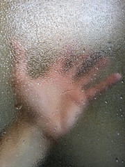Mano dietro il vetro di una doccia
